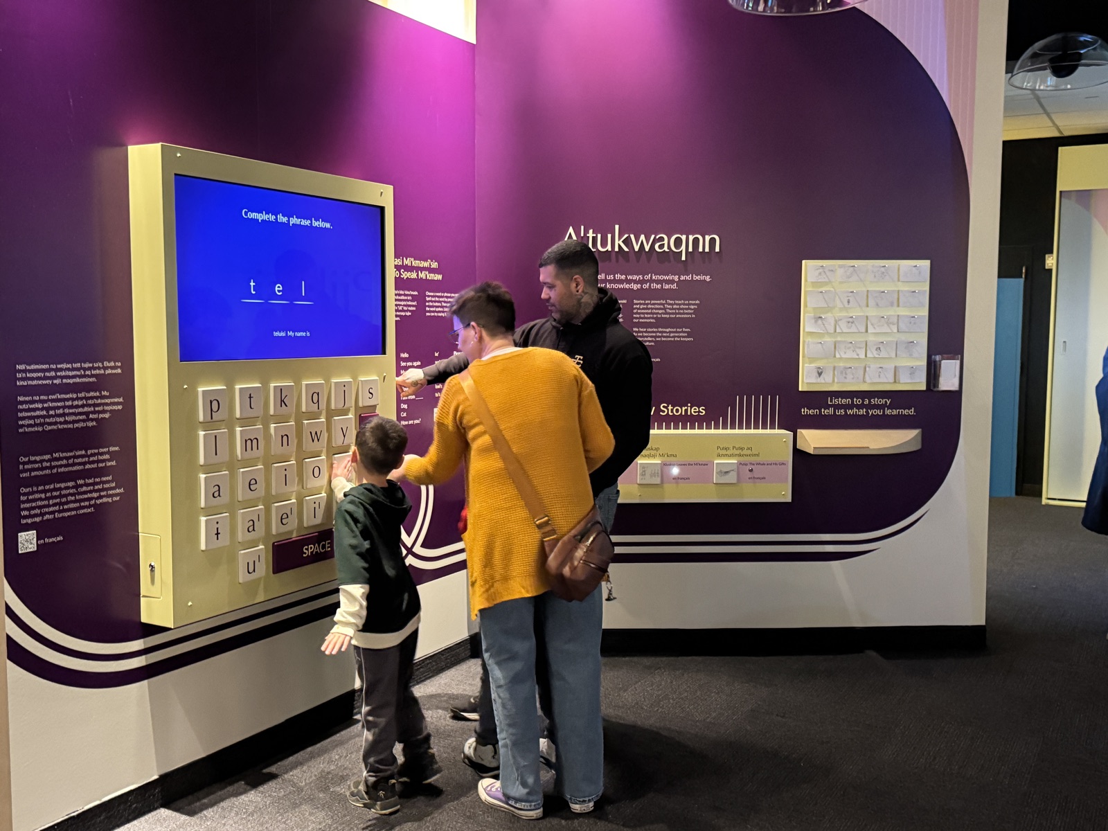 Family of three using the Mi'kmaw language keyboard station