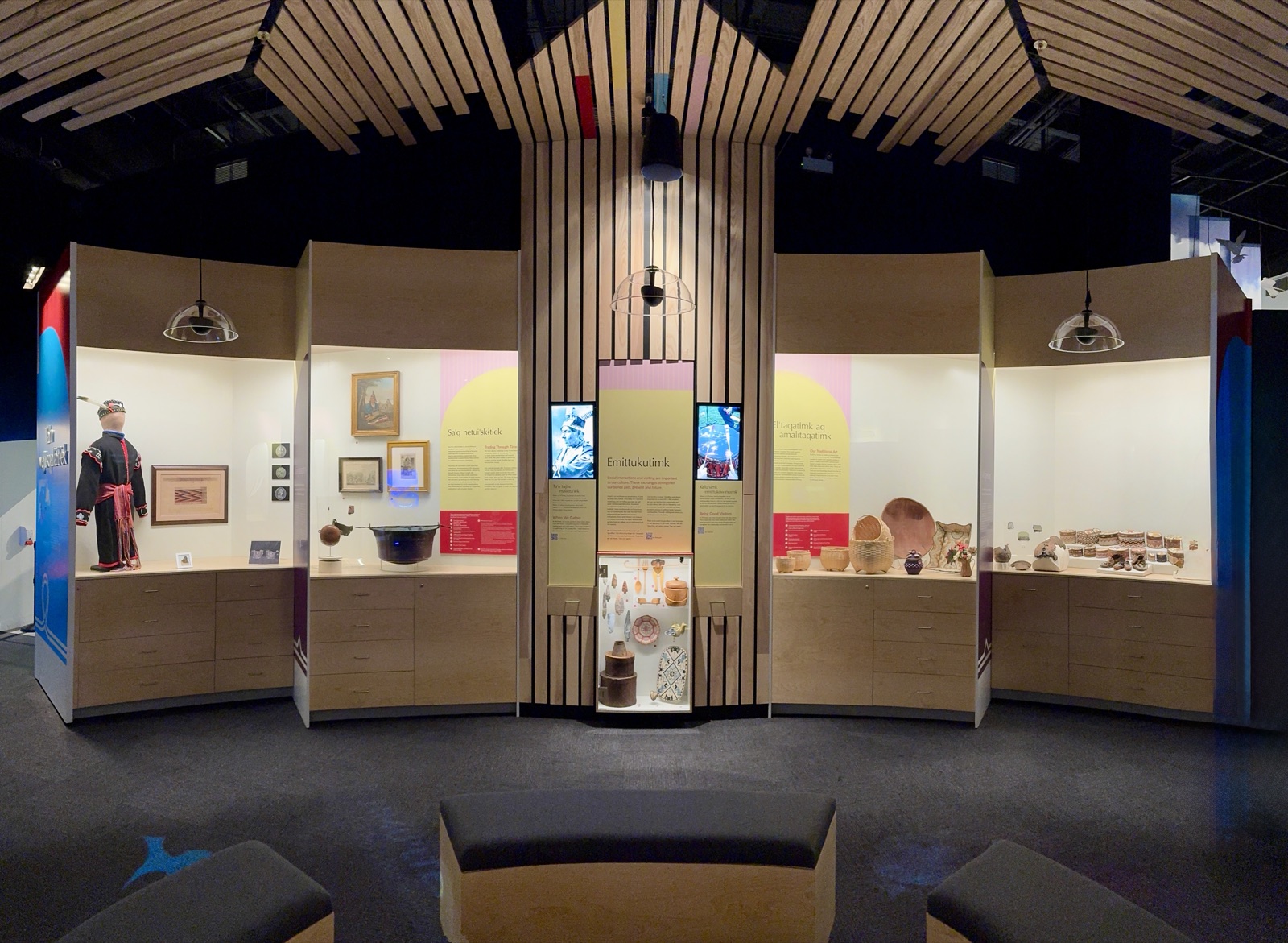 Wide view of the Pjila'si exhibit space showing artifacts, displays, and the wood-slat ceiling