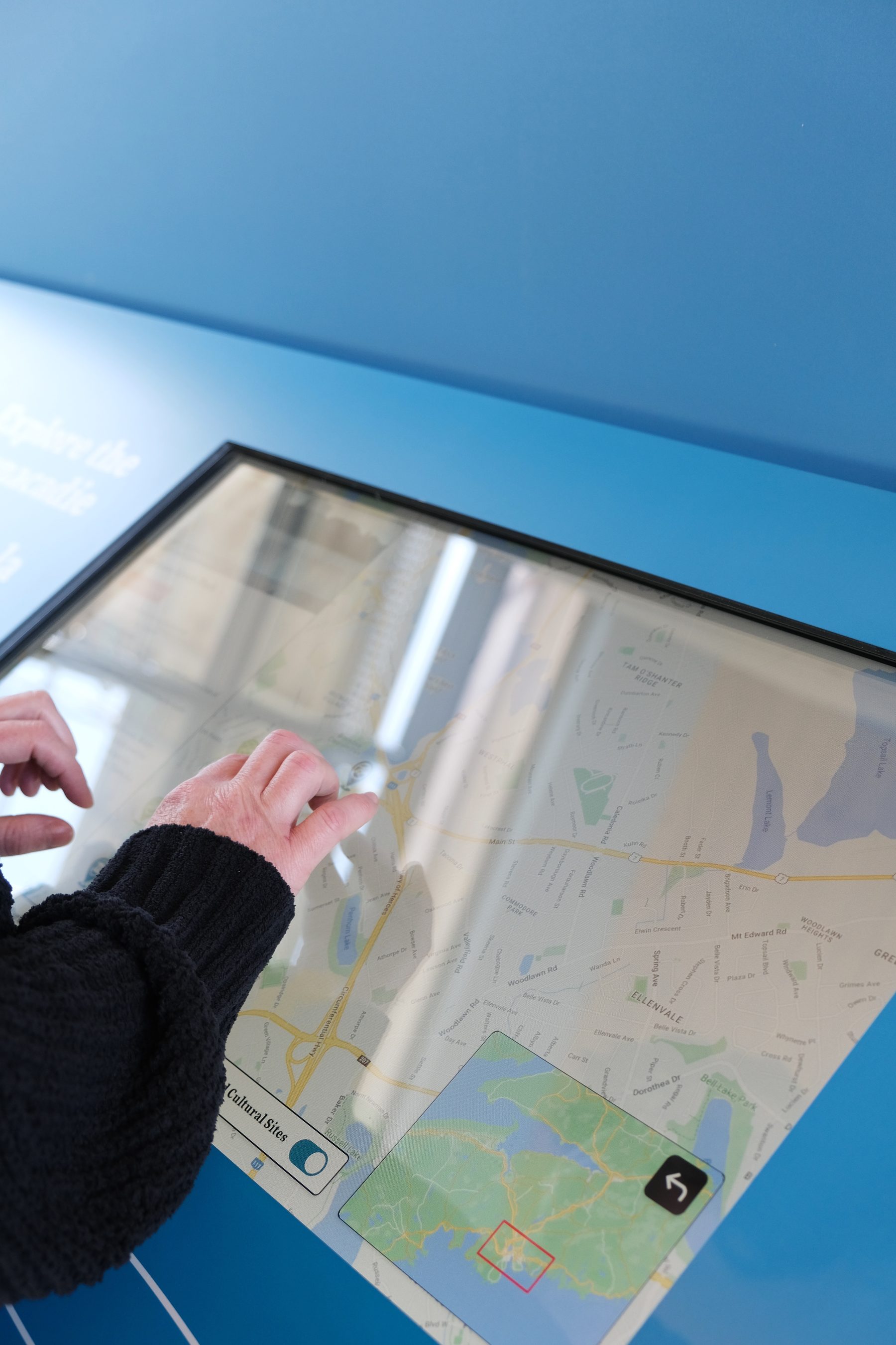 A visitor's hands on the interactive map touchscreen in the centre