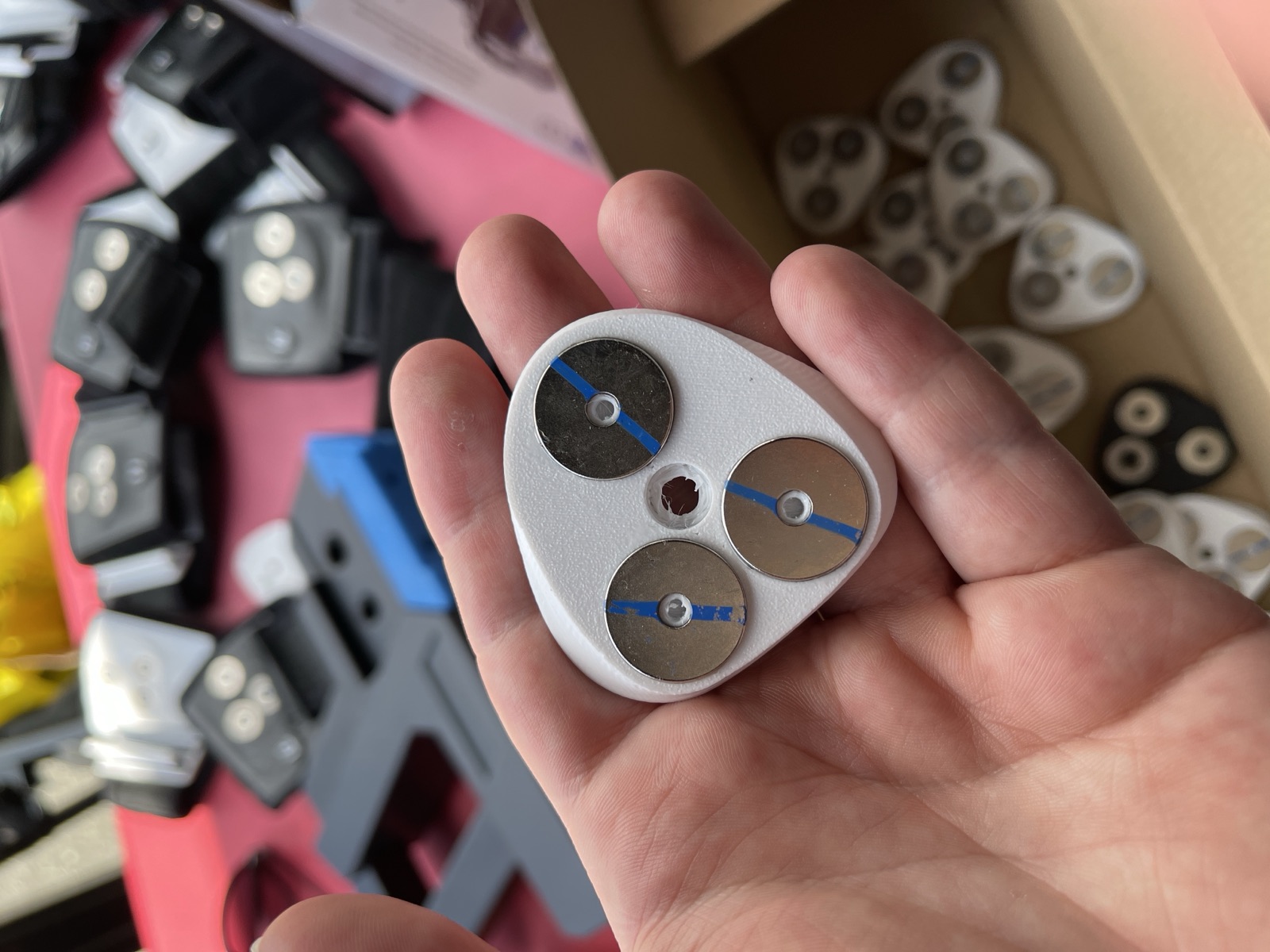 A finished 3D printed strap mount held in a hand, with the ring magnets seated in it